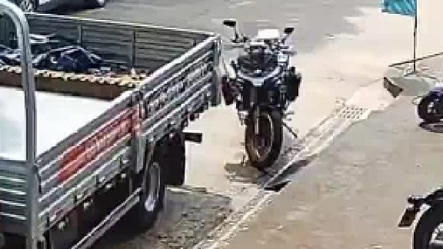 两个货车会车时白色货车不慎将路边的摩托车撞倒摩托车主正巧上完厕所赶来
