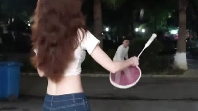 大晚上女生和好友在小区楼下打球，仔细一看还是用拍柄在打