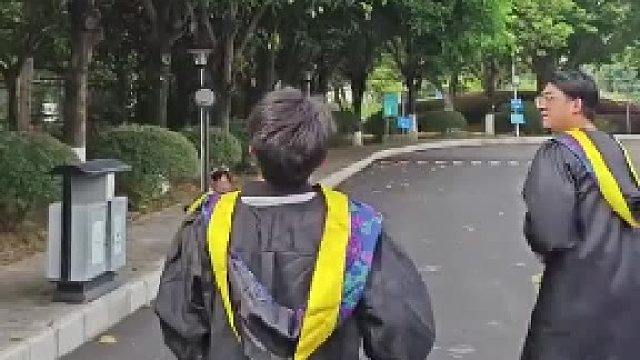 拍完毕业照后的男生们，拿着学士帽将树上的芒果打下