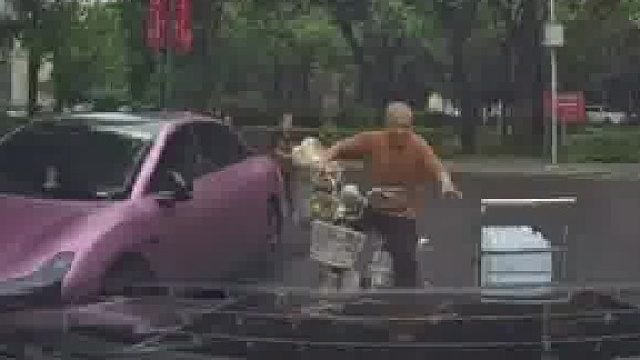 大爷一只手骑车另一只手推车，结果在路口差点与汽车迎面相撞