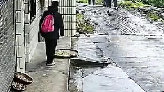 大叔到别人家屋檐凳子下躲雨，离开时，他将屋主晒的菜干踢入雨中