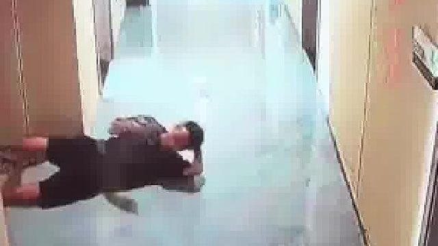 男子在酒店走廊往房间里走，却被地板滑得摔倒在地上