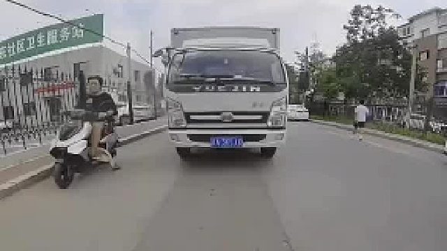 开车遇水坑溅到骑车小哥，被男子一路追赶至红绿灯，把车牌掰弯扭头就走