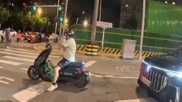 电摩在路口等红绿灯，黑车一直在后面按喇叭催促，电摩车主：滴什么滴 前面红灯啊