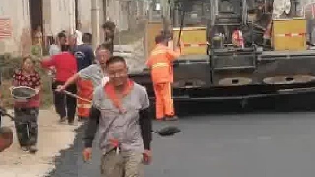 工人正在村里铺沥青路，村民纷纷拿出自家工具帮忙