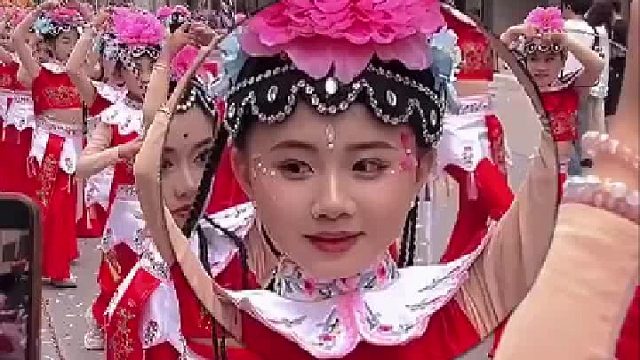 大风车舞蹈队在街上巡游，女孩拿了观众给的糖果后酸出了表情包
