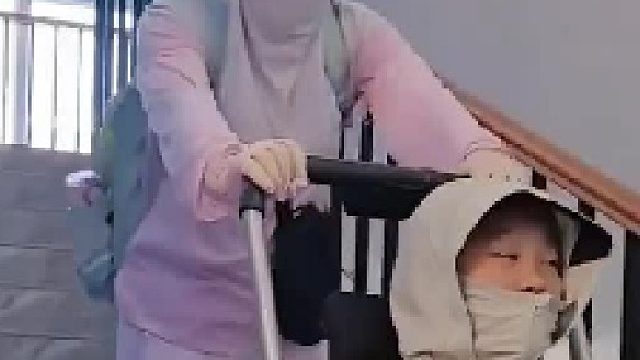妈妈陪轮椅女孩上学教室在四楼，母亲先把女儿运到教室，在把轮椅从下面抬到四楼两腿都哆嗦