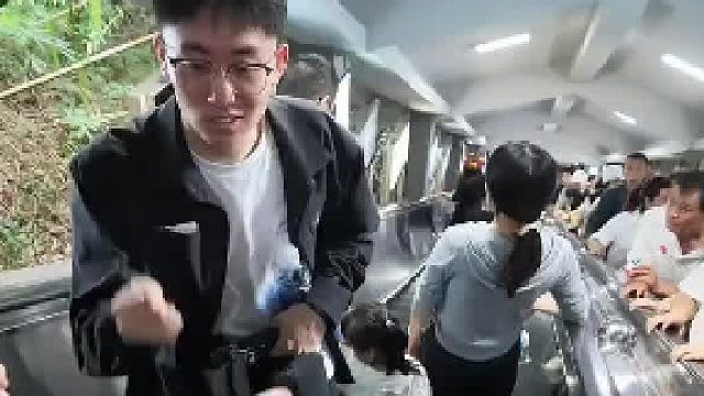 黄果树瀑布景区，扶梯上男子和朋友石头剪刀布，输了和迎面游客击掌