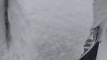 大雪后市民用木锨清理车辆上的积雪。第一步，先清理车牌。