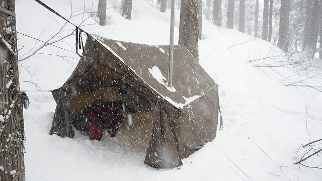 年轻小伙在下雪天独自一人前往野外搭建帐篷过夜