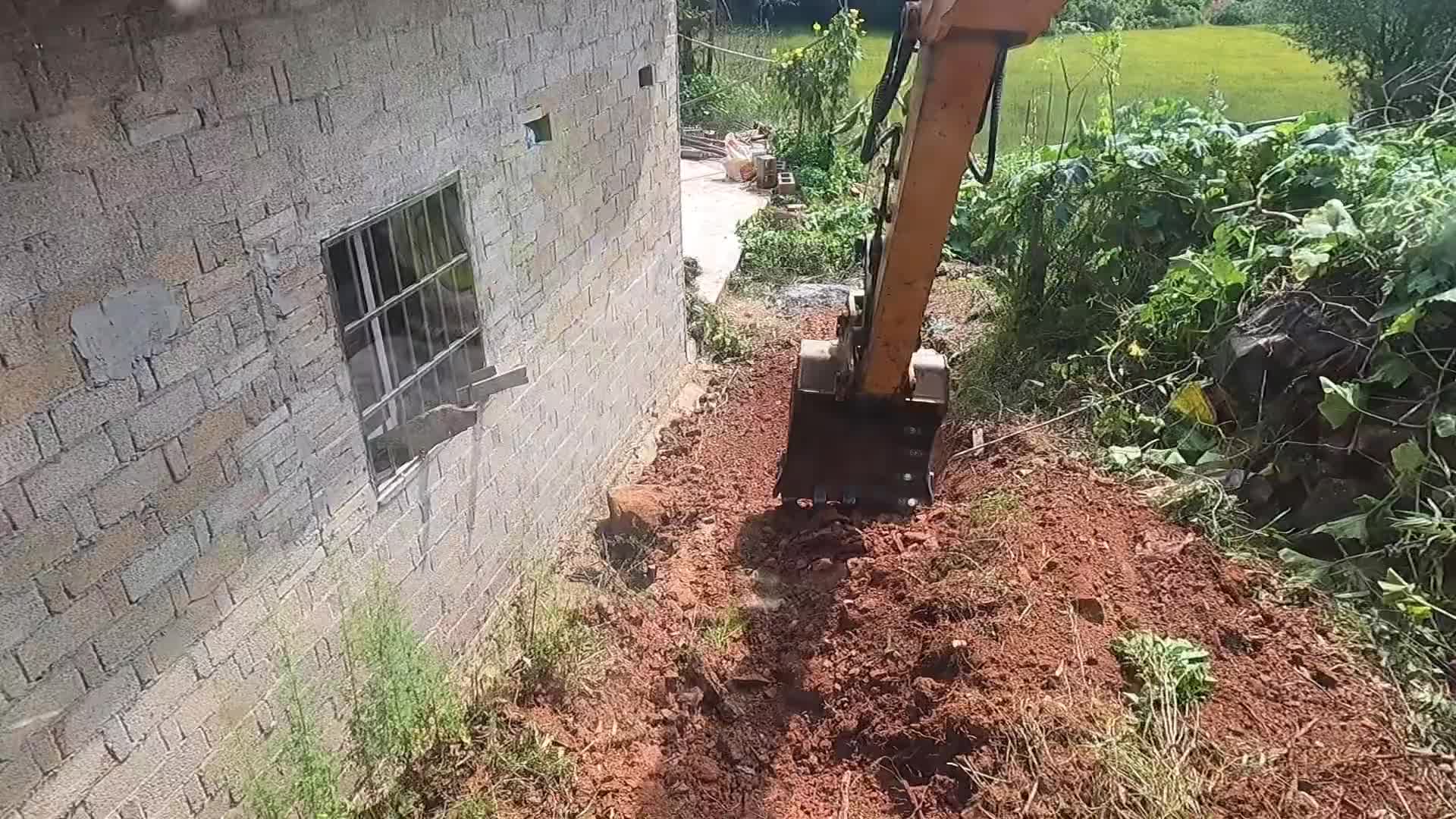 挖机清理房屋后面的石头，破碎铲斗来回切换