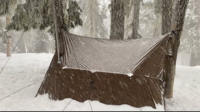 暴风雪持续下个不停，一个人在荒野露营生存，燃起火炉煮饭取暖，木材准备充足，夜晚睡觉很暖和