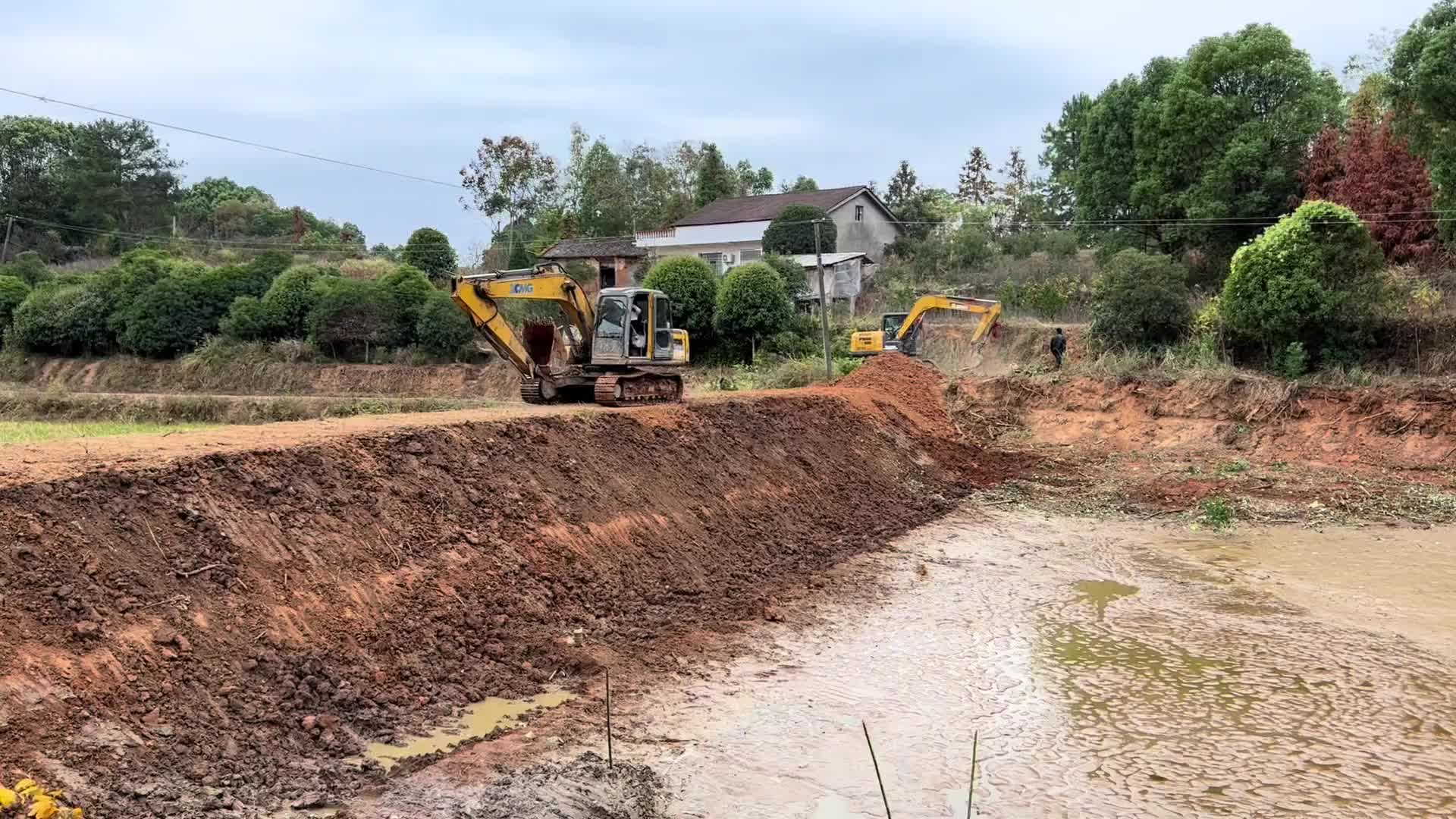 挖鱼塘整堤坝，清理鱼塘泥巴。大小两个挖机合作