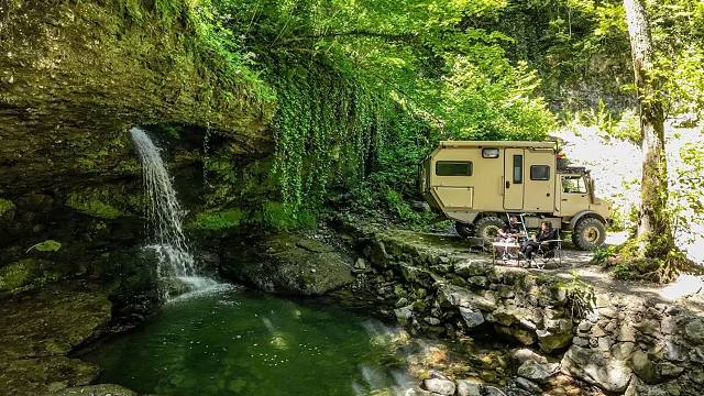 夫妻二人真是太会找地方了，开着军用卡车，在一个瀑布山泉极致露营