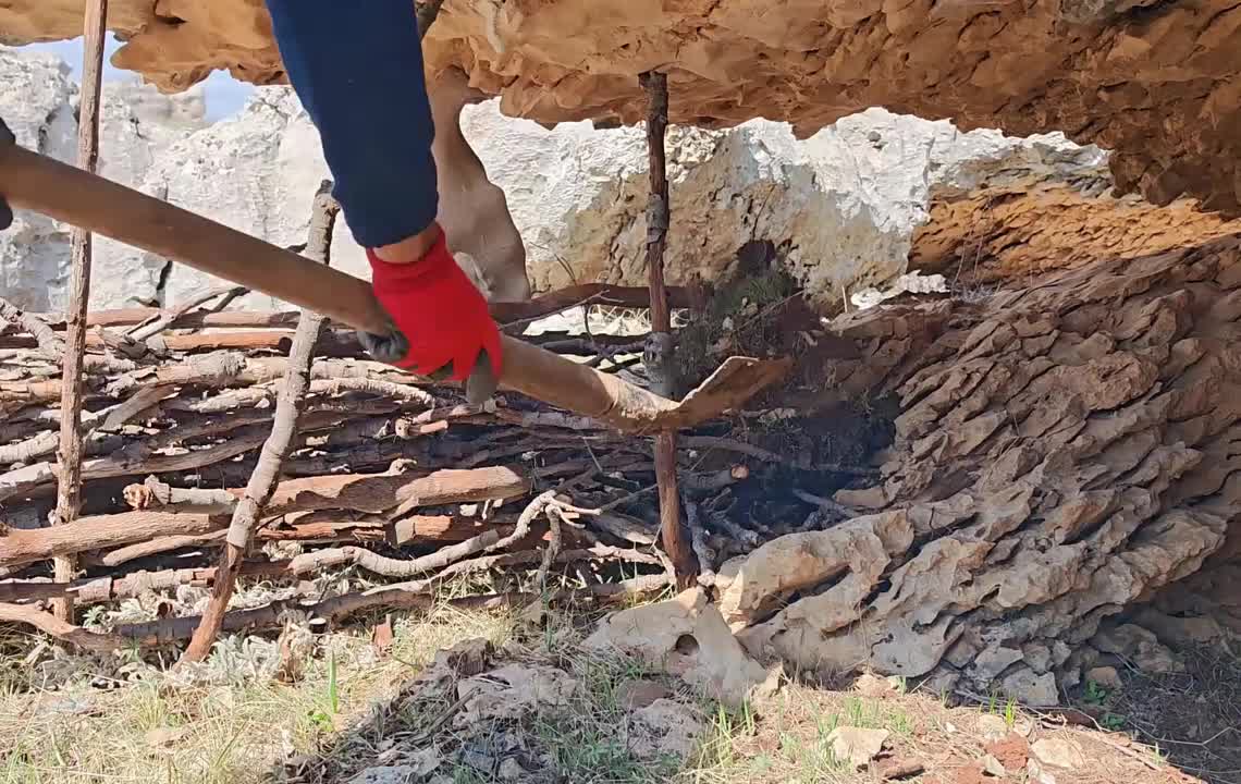 男人在一个巨石下搭建了舒适的小屋