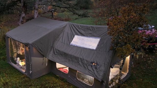 一男一女，靠着顶超级帐篷，在野外享受五星级豪华露营