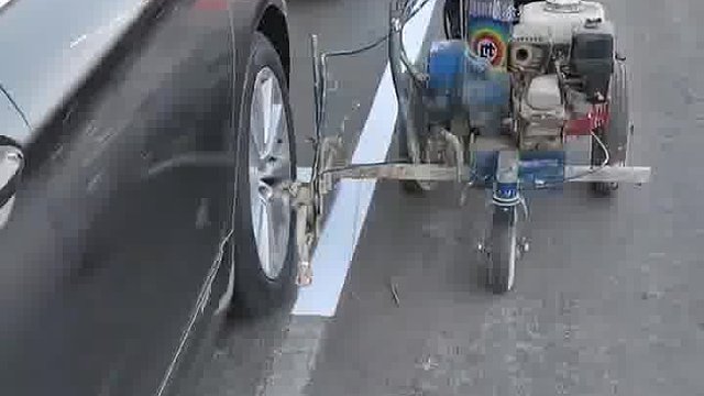 道路停车位划线时的一幕，小车侧方停车一个车轮压到了线！