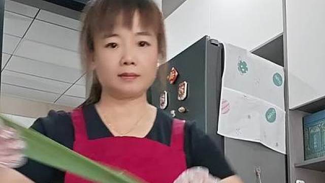 围裙一系，热情满满，手里的粽叶舞动出生活的节奏感。无论是包粽子还是分享快乐，都是对传统手艺的致敬。每一颗粽子都藏着满满的爱意和对家的思念，让人忍不住想立刻尝一口！