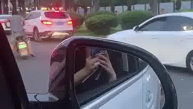骑电动车男子往白色轿车上扔水瓶，白车司机加油门冲又刹住。