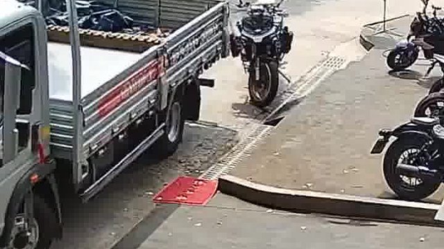 两个货车会车时，白色货车不慎将路边的摩托车撞倒，摩托车主正巧上完厕所赶来