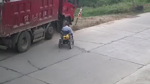 老人坐轮椅横穿马路，货车为避让老人撞毁路障。