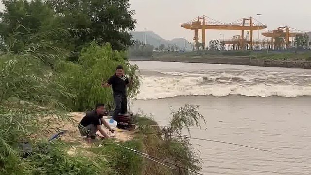 俩小伙在河边钓鱼，突遇涨潮，没见过潮水的他们有点懵！